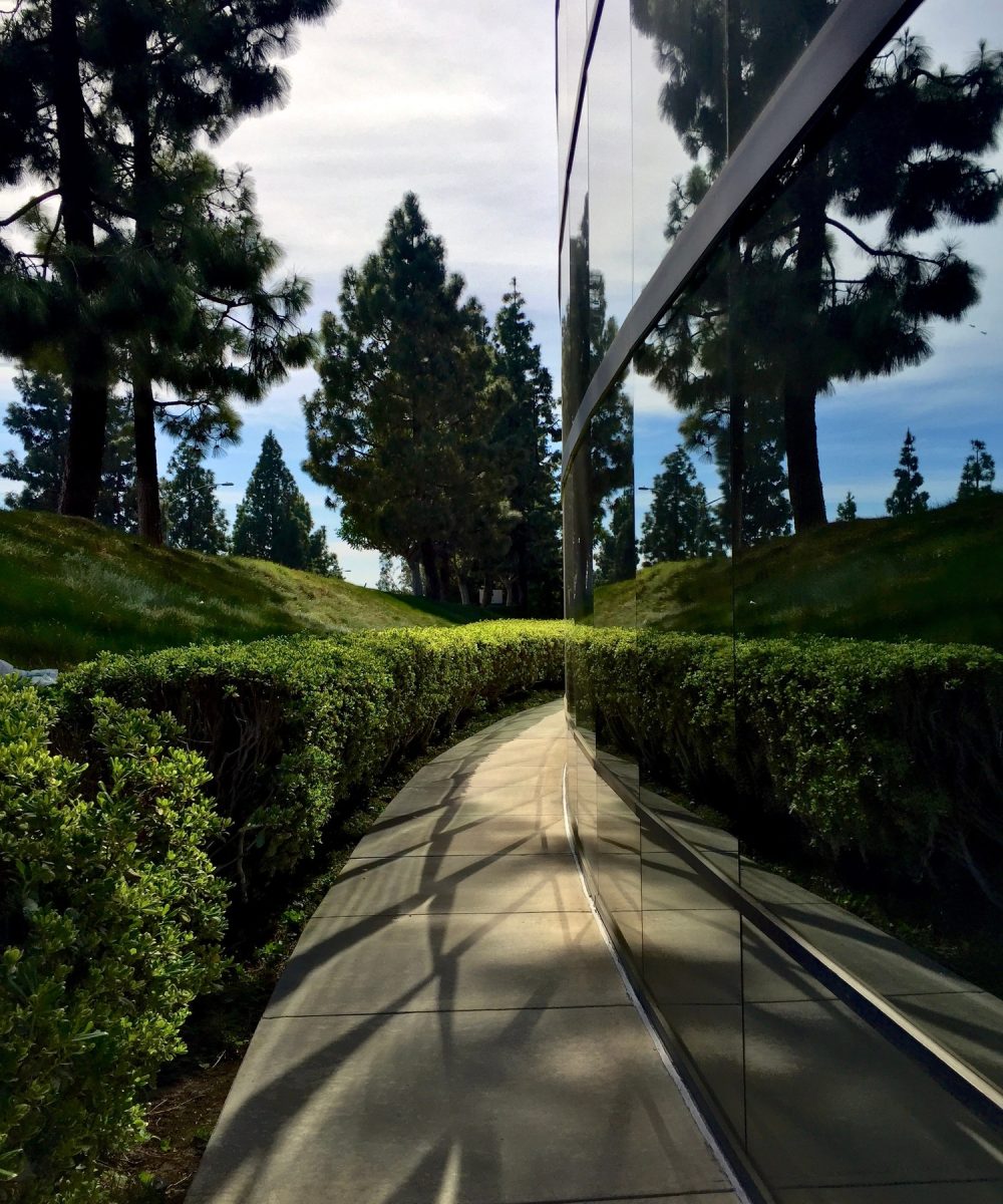 Walking path around a modern building with curved, mirrored glass windows